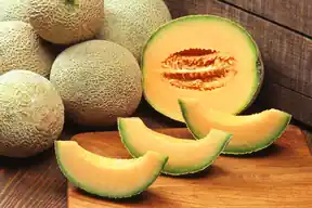 Whole netted cantaloupes and sliced orange cantaloupe wedges